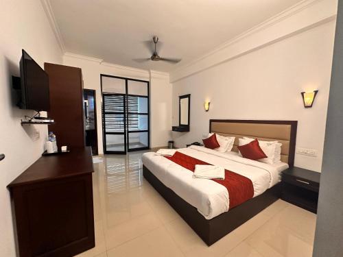 um quarto com uma cama grande e uma televisão em Luxe Hotel Thekkady em Thekkady