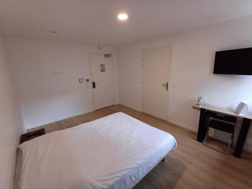 Dormitorio con cama, escritorio y TV en CRYSTAL HOTEL, en Claye-Souilly