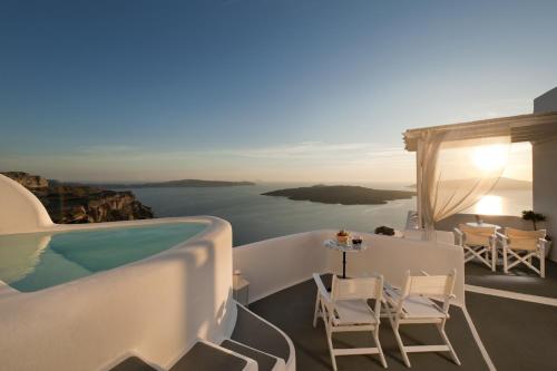 a villa with a pool and a table and chairs at Kamares Apartments in Fira