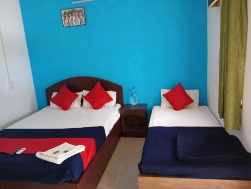 two beds in a room with blue and red pillows at Neil Holiday Resort in Neil Island