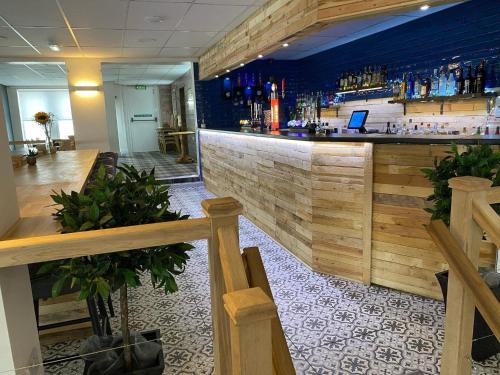 a bar in a restaurant with a wooden wall at Waverley Hotel in Workington