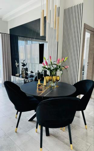 a black dining room table with black chairs and flowers at Apartamenty BLUE BALTIC SPA Jacuzzi & Sauna MORZE in Chłopy