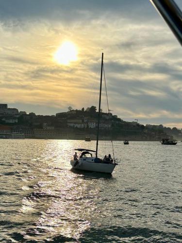 a sail boat in the water with the sun setting at Navegar no Douro - Navegação e Turismo Unipessoal, Lda in Vila Nova de Gaia