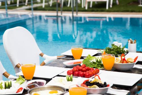 a table with food and drinks next to a swimming pool at Assos Altın Hotel in Behramkale