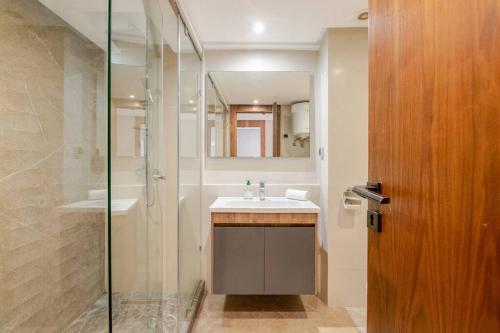 ein Bad mit einem Waschbecken und einer Dusche mit einem Spiegel in der Unterkunft TT Holidays Cosy Apartment/ Casablanca City in Casablanca