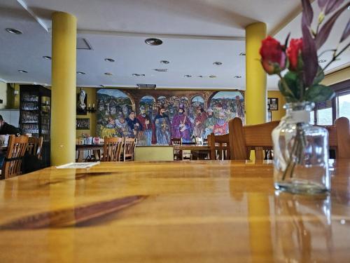 Una mesa en un restaurante con un jarrón de flores. en Albergue el convento de Foncebadon, en Foncebadón
