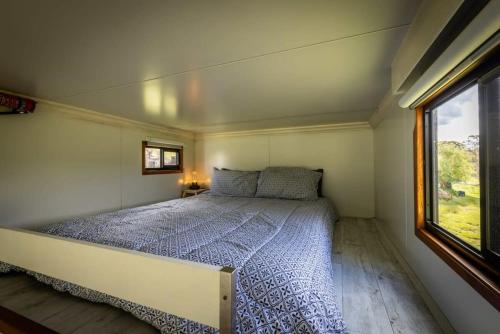 Bett in einem kleinen Zimmer mit Fenster in der Unterkunft Sithuri Tiny House in Windeyer