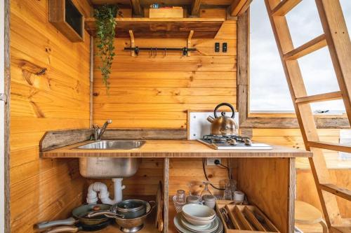 uma cozinha numa pequena casa com um lavatório em Altitude - A Tiny House Experience in a Goat Farm em Romsey