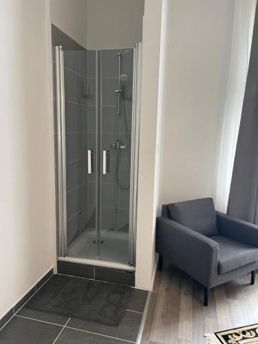 a glass shower in a bathroom with a blue chair at King David Garden in Berlin