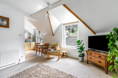 a living room with a flat screen tv and a table at Apartment in the heart of Beer on Jurassic Coast in Beer