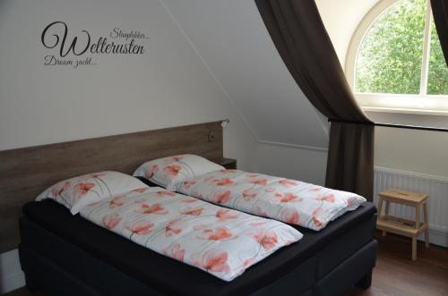 a bed with two pillows on it next to a window at Vakantiehuis B&B Familie Versantvoort in Handel