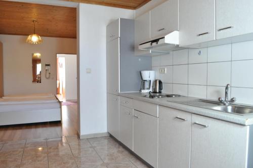 uma cozinha com armários brancos e um lavatório em Appartmenthaus Rosenhof em Podersdorf am See