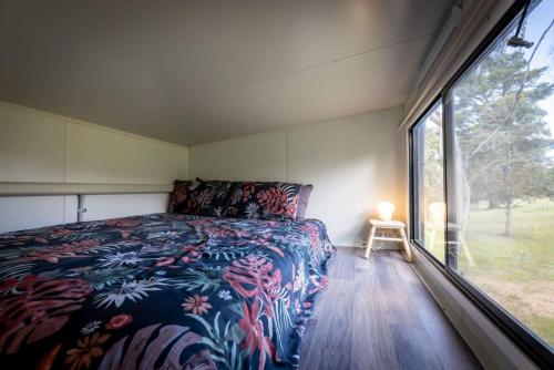 a bedroom with a bed and a large window at Tiny House Farmstay at Dreams Alpaca Farm - A Windeyer Outback Experience in Windeyer