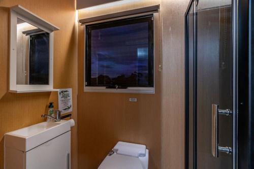 a bathroom with a toilet and a sink and a window at Tiny House Big View in Boneo