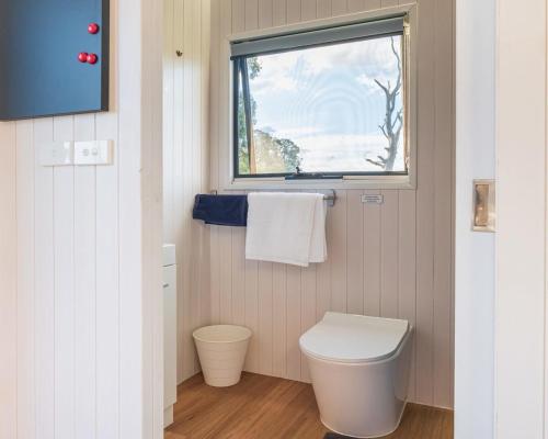 a bathroom with a toilet and a window at Farm Tiny in Braidwood