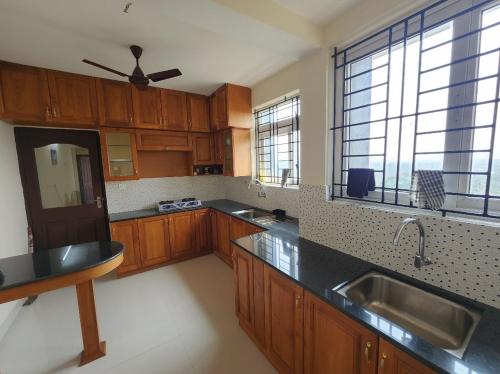 a kitchen with wooden cabinets and a black counter top at Sharon Holidays Near LULU in Trivandrum