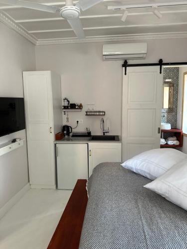 a white bedroom with a bed and a kitchen at Castellorizon Pensione in Meyisti
