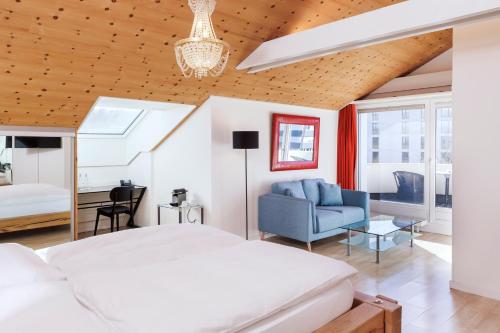 a bedroom with a white bed and a blue couch at Sorell Hotel Sonnental in Dübendorf