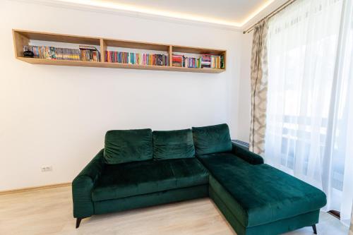 a green couch in a living room with a book shelf at Cross Caraiman View 1 in Buşteni