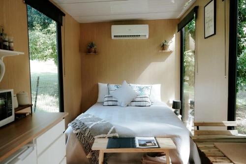 1 dormitorio con 1 cama en una habitación con ventanas en Cockatoo Cabin, en Palmwoods