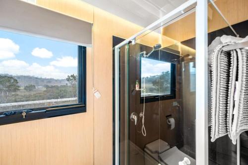 a bathroom with a glass shower with a window at Cabernet Tiny House in Windeyer