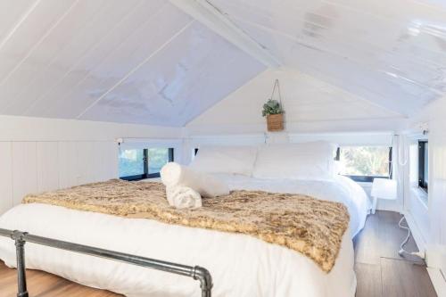 - une chambre blanche avec un grand lit dans l'établissement Wombat Cottage, à Crackenback