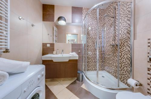 a bathroom with a shower and a tub and a sink at Aquarius Kołobrzeg in Kołobrzeg