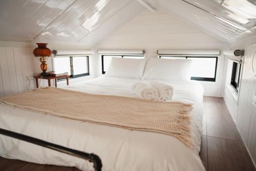 ein Schlafzimmer mit einem großen weißen Bett mit Handtüchern darauf in der Unterkunft Tiny Regen Farm Stay in Lawrence
