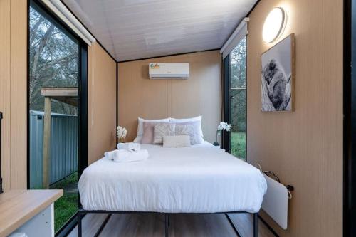 a bedroom with a large white bed and some windows at Prunus Hideaway 