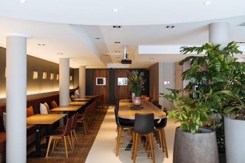 a row of tables in a restaurant with plants at Cosmopolite Hotel Nieuwpoort-Bad in Nieuwpoort