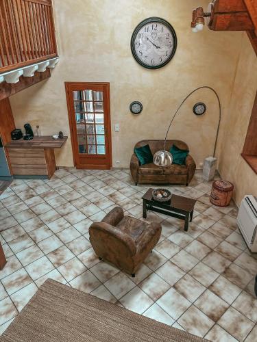 un salon avec un canapé et une horloge au mur dans l'établissement logement proche de nimes, à Nîmes