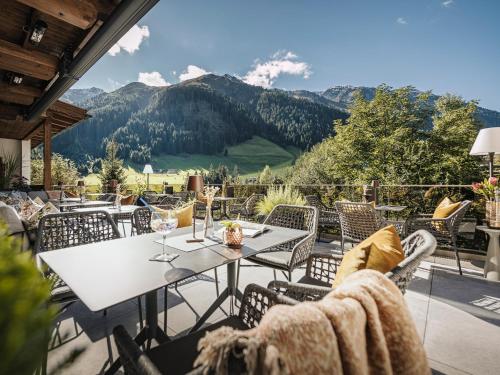 a patio with a table and chairs and mountains at Hotel Bergkristall Zillertal in Hippach