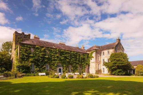 um grande edifício de pedra com hera crescendo sobre ele em Ballymaloe House Hotel em Ballycotton