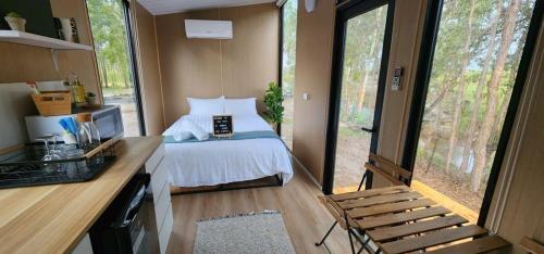 a bedroom in a tiny house with a bed and a desk at Hidden Camp Pie Creek in Gympie