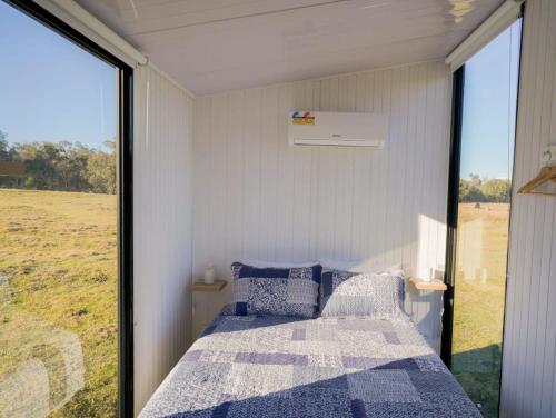 um quarto com uma cama e uma grande janela em Little Argyle Tiny House em Coonabarabran