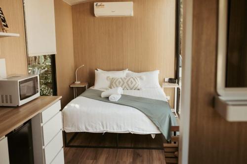 ein kleines Schlafzimmer mit einem Bett und einer Mikrowelle in der Unterkunft The Stables in Palmwoods