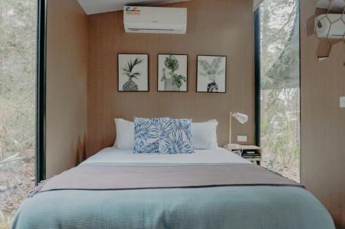 a bedroom with a bed with four pictures on the wall at Wilderness View in Mooloolah