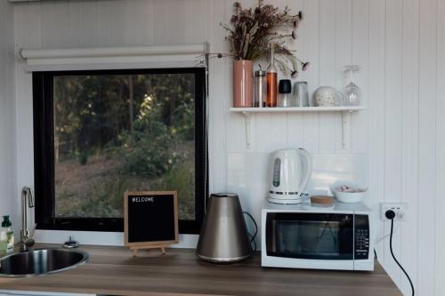 a kitchen counter with a microwave and a window at Tiny Tamborine 2 in Wongawallan