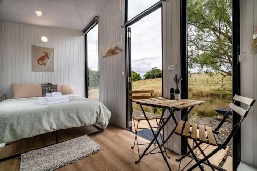 a bedroom with a bed and a table and a window at The Meadows Tiny House in Macclesfield