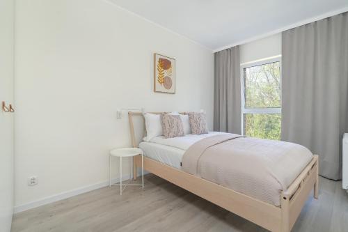 a white bedroom with a bed and a window at Family Apartment in Poznań with 2 Parking Spaces, 3 Bedrooms and Balcony by Renters in Poznań