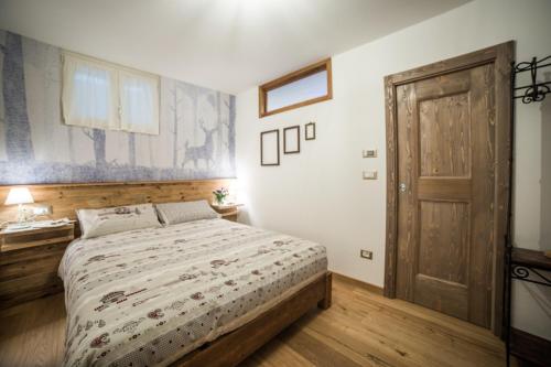 1 dormitorio con 1 cama y puerta de madera en B&B Ca' La Vedescia, en Teglio