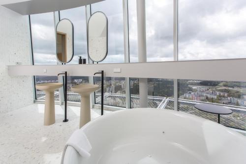 a bathroom with a white tub and mirrors at Vilnius TV Tower Apartments DEBESYS in Vilnius