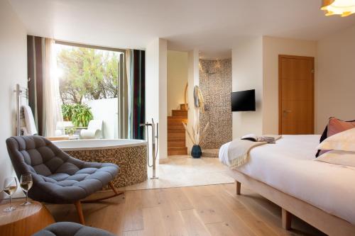 um quarto com uma cama, uma cadeira e uma banheira em Scarlet Hotel em Mawgan Porth