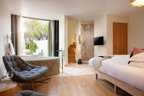 a bedroom with a bed and a chair and a tub at Scarlet Hotel - Adults Only in Mawgan Porth