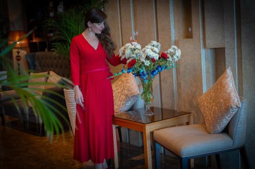 a woman in a red dress standing next to a vase of flowers at Copthorne Hotel Sharjah in Sharjah
