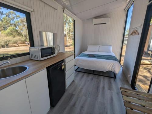 a small bedroom with a bed and a sink in a trailer at Tiny House 8 at Grampians Edge in Dadswells Bridge