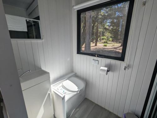 a small bathroom with a toilet and a window at Tiny House 8 at Grampians Edge in Dadswells Bridge