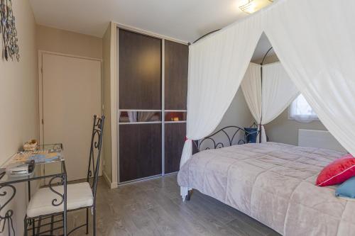 um quarto com uma cama de dossel, uma secretária e uma mesa em Villa - Spa Terre et Mer em Landévant