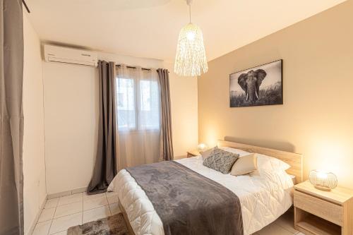 1 dormitorio con cama y lámpara de araña en sunny, en Saint-Gilles-les-Bains
