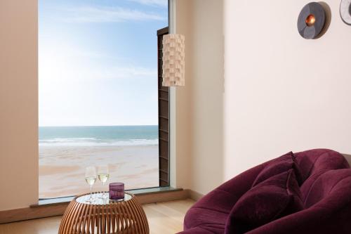a living room with a chair and a table with wine glasses at Scarlet Hotel - Adults Only in Mawgan Porth